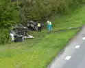 Auto en aanhanger met graafmachine over de kop