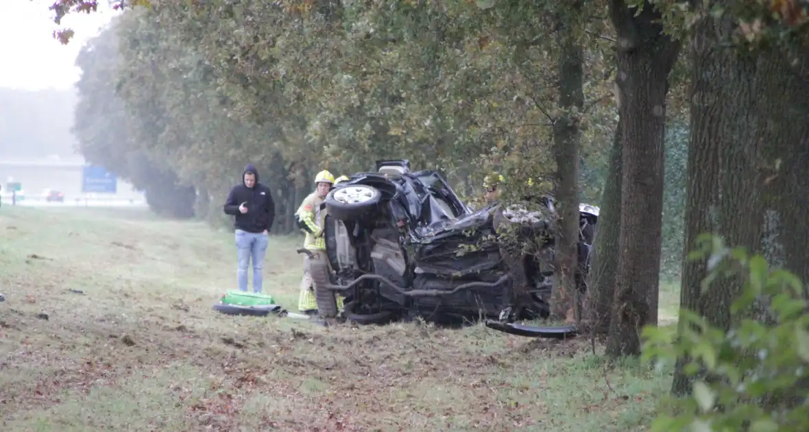 Auto zwaar beschadigd na botsing tegen boom langs snelweg - Foto 1