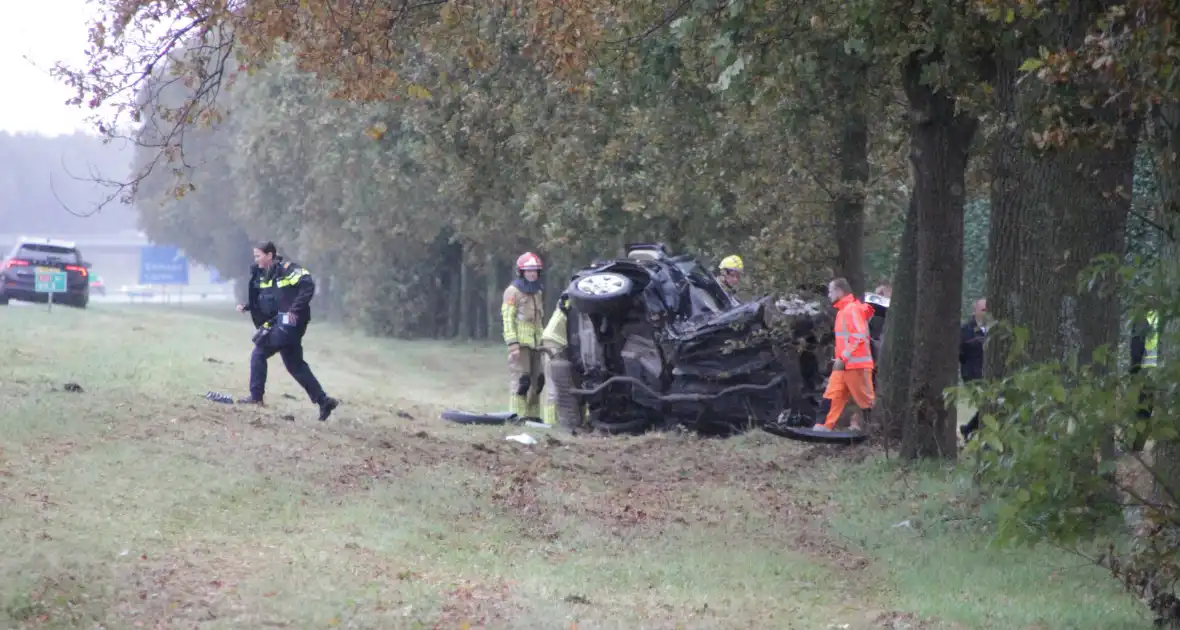 Auto zwaar beschadigd na botsing tegen boom langs snelweg - Foto 9