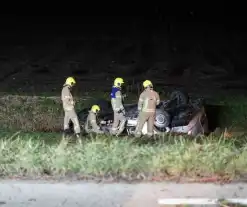 Auto raakt van weg, schampt boom en belandt ondersteboven in de sloot