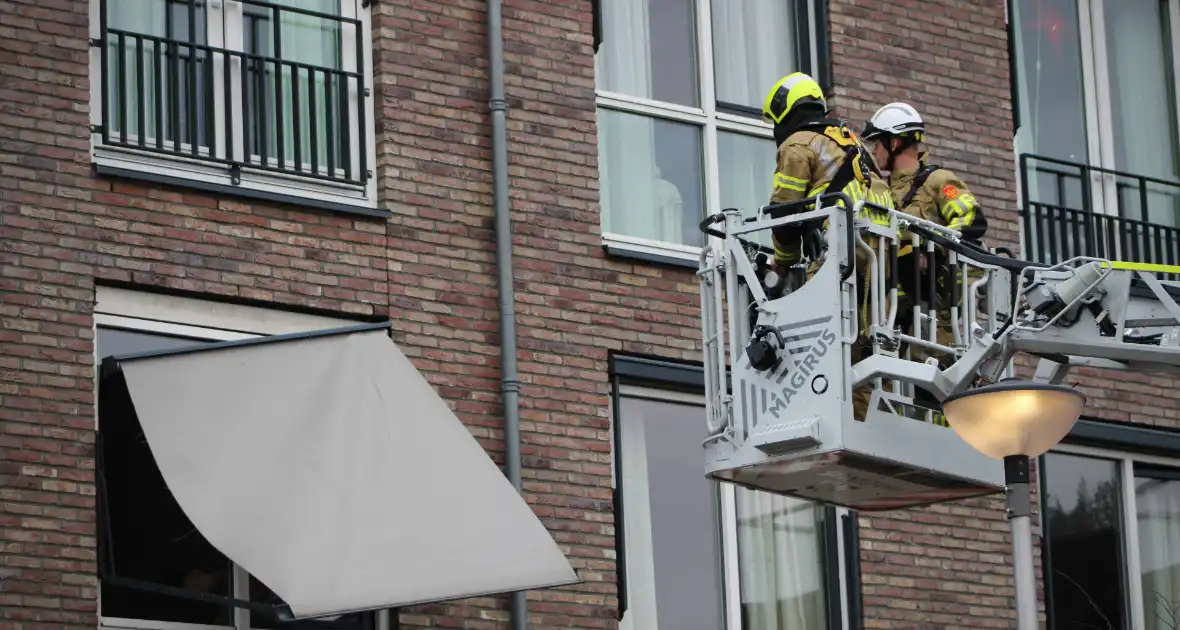 Brandweer zet loshangende zonnescherm vast