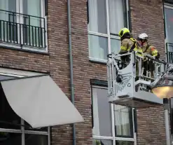 Brandweer zet loshangende zonnescherm vast