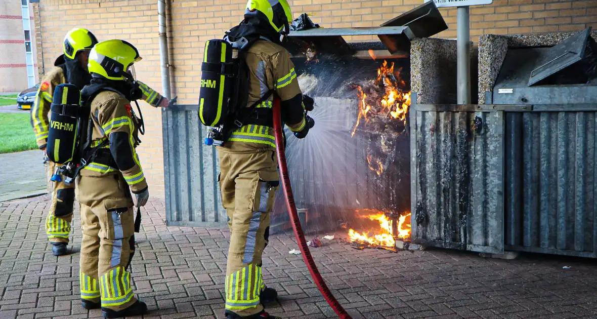 Containers onder flatgebouw in brand