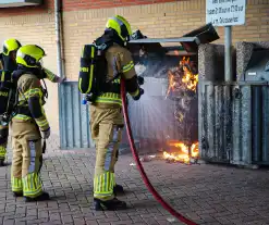 Containers onder flatgebouw in brand