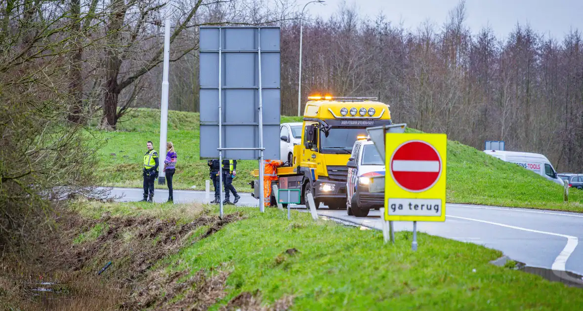 Auto raakt van de weg in bocht van afrit