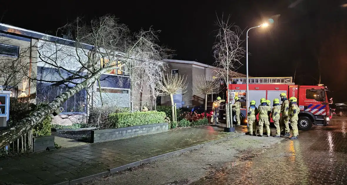 Grote boom waait om en belandt tegen woning