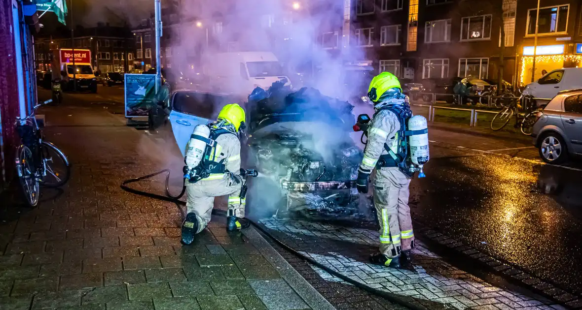 Brandweer blust in brand staande auto