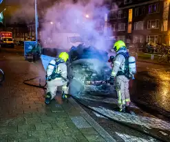 Brandweer blust in brand staande auto