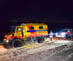 Politiejeep muurvast in los zand op strand