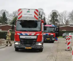 Brandweer blust brandend afval achter sloopwoningen