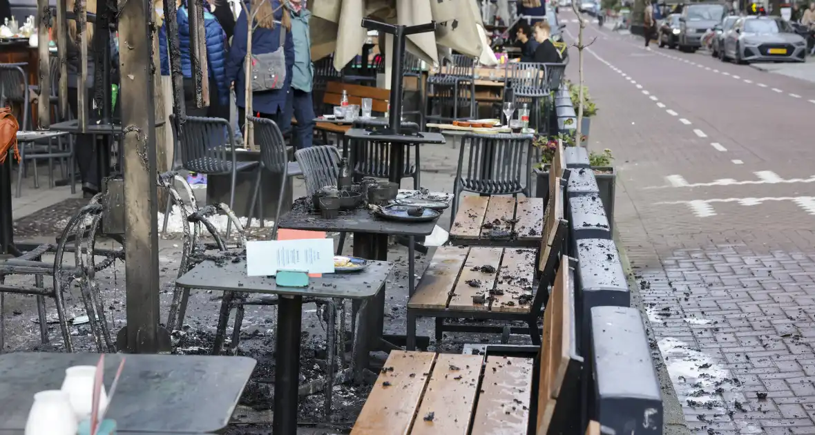 Parasol vat vlam op terras van café - Foto 17