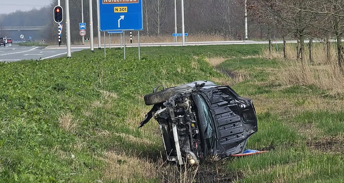 Auto ramt verkeerslicht en belandt op zijn zij in een greppel