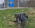 Auto ramt verkeerslicht en belandt op zijn zij in een greppel