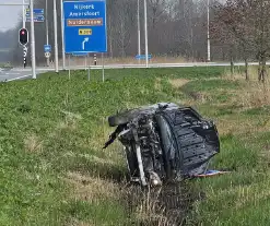 Auto ramt verkeerslicht en belandt op zijn zij in een greppel