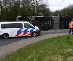 Vrachtwagencombinatie met zand kantelt op rotonde