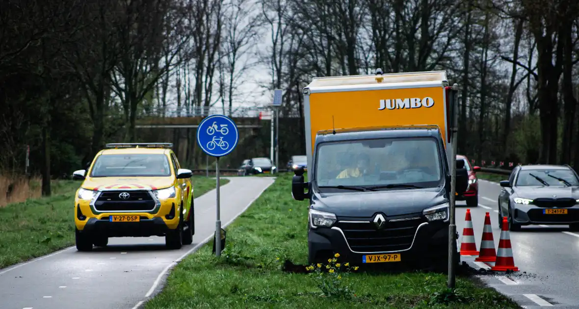 Jumbo bezorger raakt met bakwagen van weg en komt vast te zitten