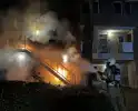 Brandweer blust brandende container onder trap