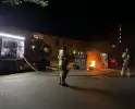 Brandweer blust brandend afval naast container