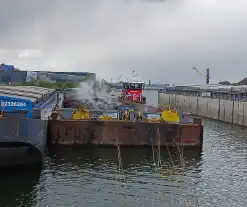 Brandweerboot inspecteert dampende duwbak