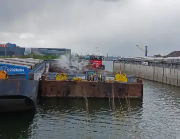 Brandweerboot inspecteert dampende duwbak
