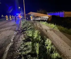 Vrachtwagen ramt boom en belandt op zijkant in sloot