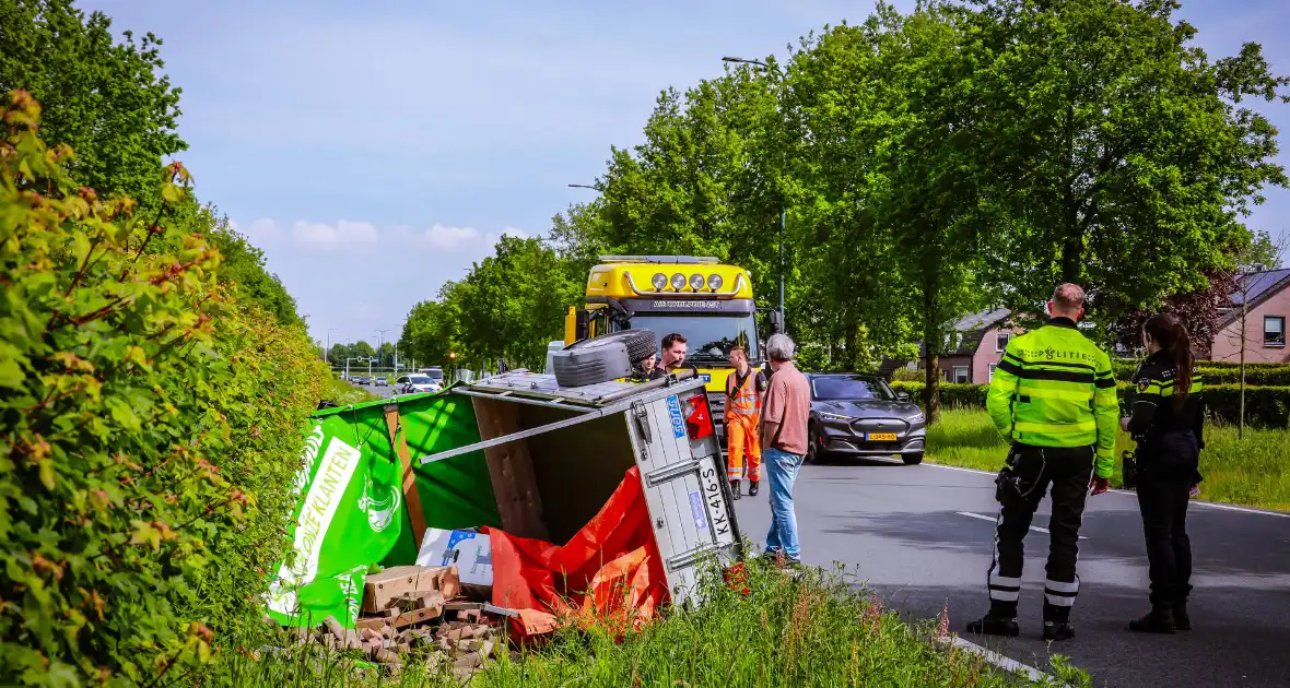 Aanhanger geladen met stenen belandt op zijn kant