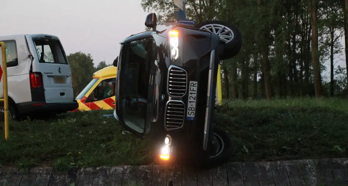 Auto op zijn kant na opmerkelijk ongeval op rotonde - Foto 1