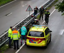 Motorrijder hard onderuit door water onder viaduct