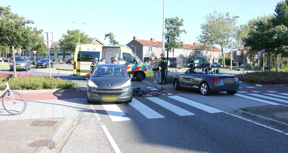 Fietser klapt op zijkant van auto tijdens het oversteken op rotonde - Foto 1