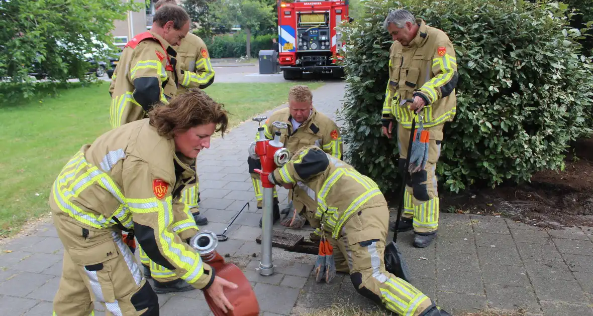 Brandweer blust buitenbrand met water uit brandkraan - Foto 2