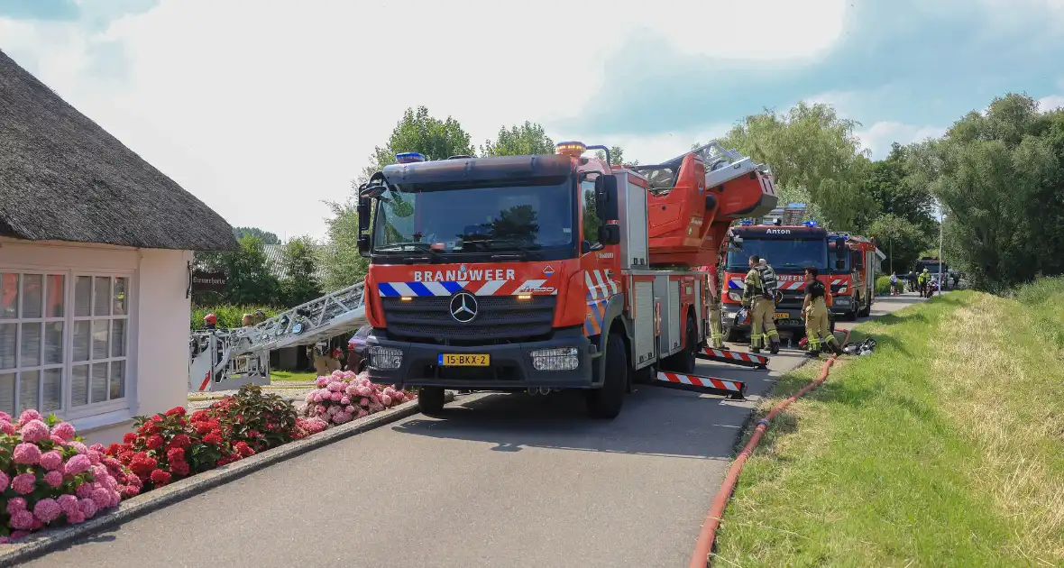 Brandweer blust brand in rietenkap van woning