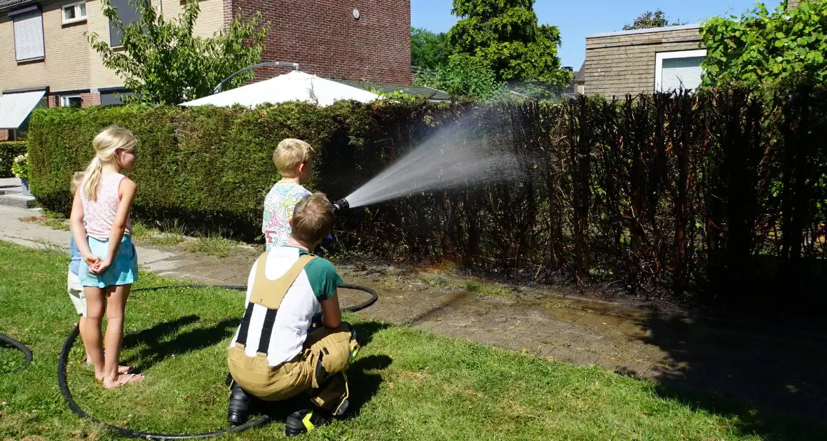 Kinderen blussen met brandweer brandende coniferenhaag - Foto 1