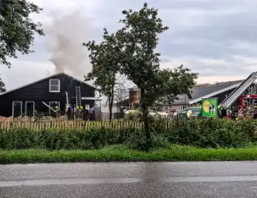 Brandweer blust brandende tussenmuur bij boerderij