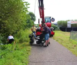 Man met scootmobiel in droge sloot: Jongens van Oranjevereniging bieden hulp