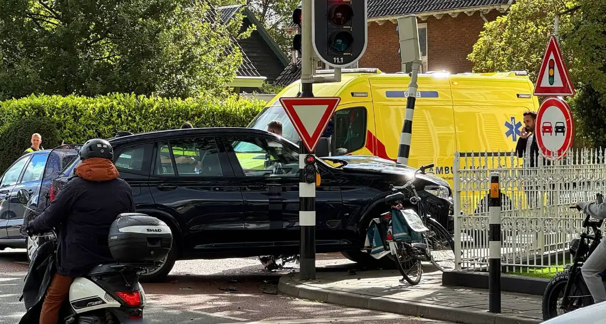 Twee voertuigen botsen op elkaar waarna een op een verkeerslicht klapt