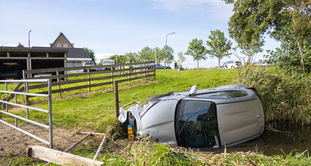 Omstanders halen automobilist uit te water geraakte auto