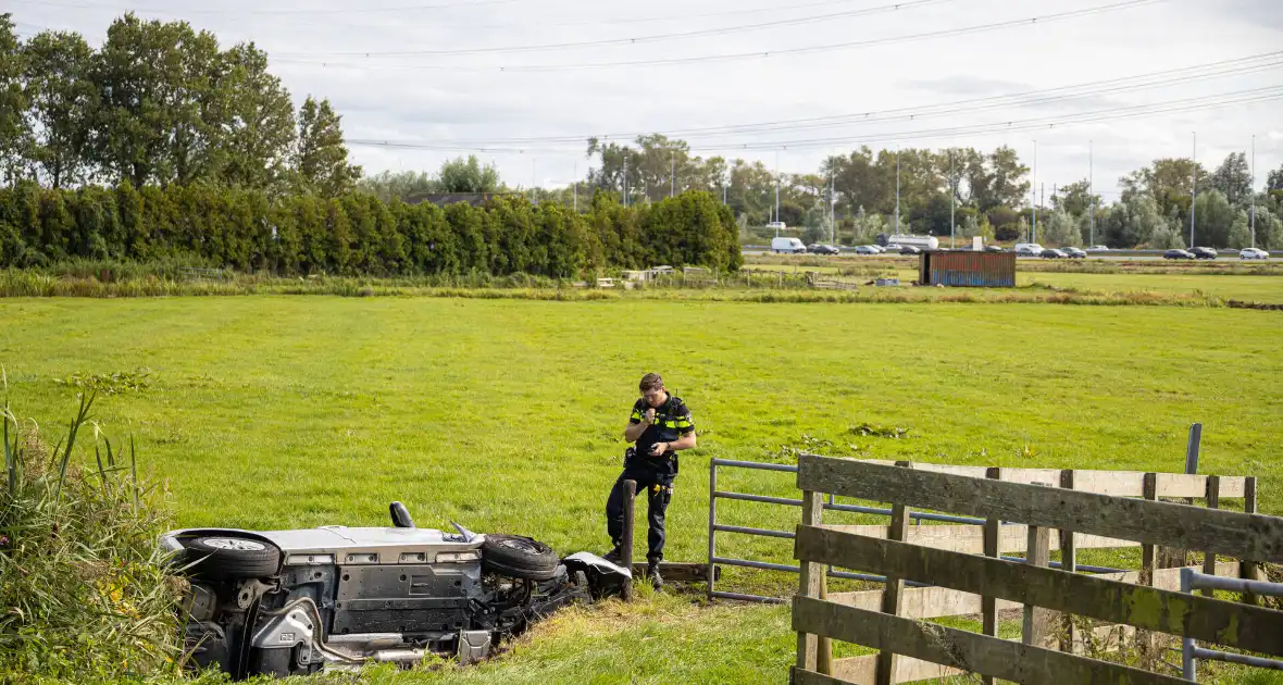 Omstanders halen automobilist uit te water geraakte auto - Foto 1