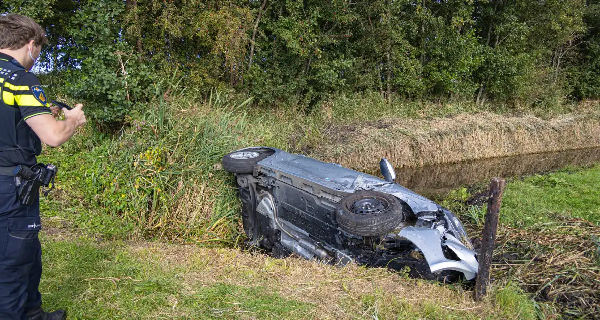 Omstanders halen automobilist uit te water geraakte auto - Foto 3