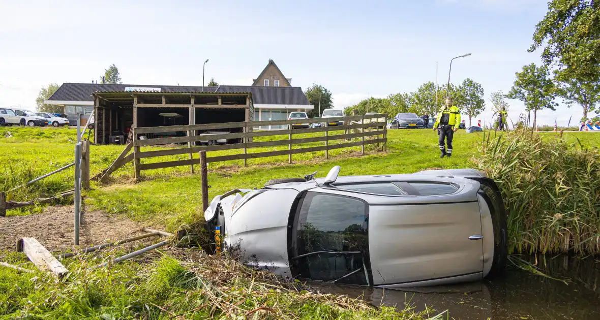 Omstanders halen automobilist uit te water geraakte auto - Foto 7