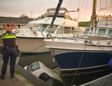 Auto rolt jachthaven in en gaat kopje onder