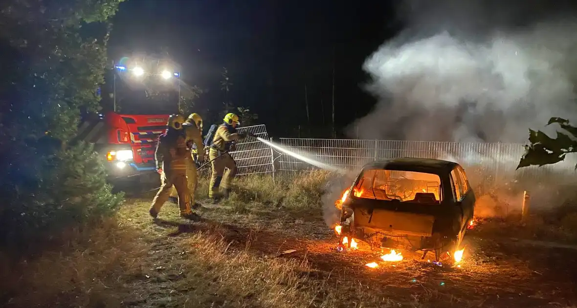 Brandweer blust brandende auto in bosgebied