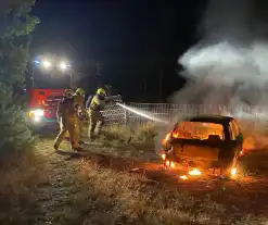 Brandweer blust brandende auto in bosgebied