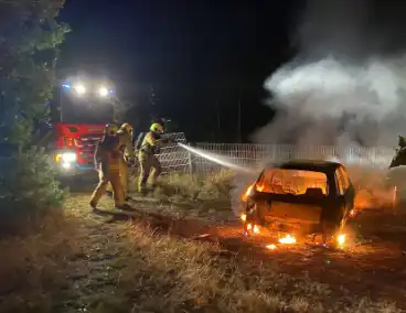 Brandweer blust brandende auto in bosgebied