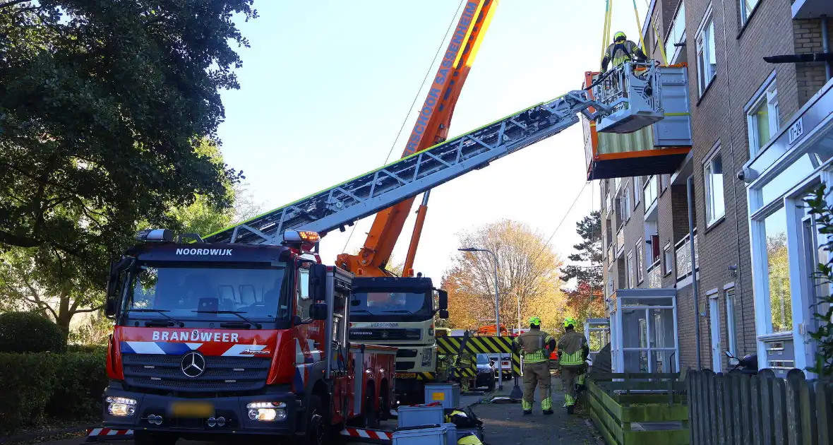 Persoon door hijskraan uit flatwoning getakeld