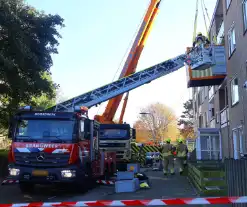 Persoon door hijskraan uit flatwoning getakeld