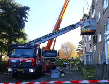 Persoon door hijskraan uit flatwoning getakeld