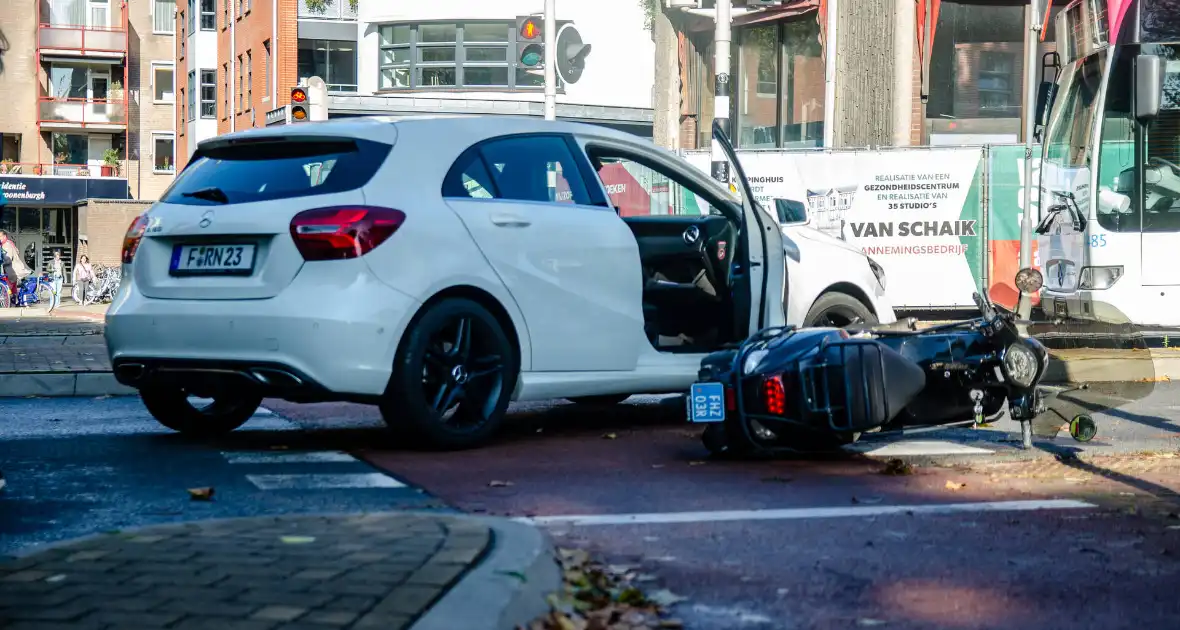 Scooter rijdt in zijkant van auto