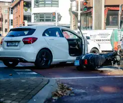 Scooter rijdt in zijkant van auto