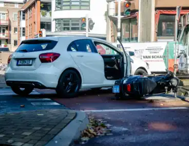 Scooter rijdt in zijkant van auto