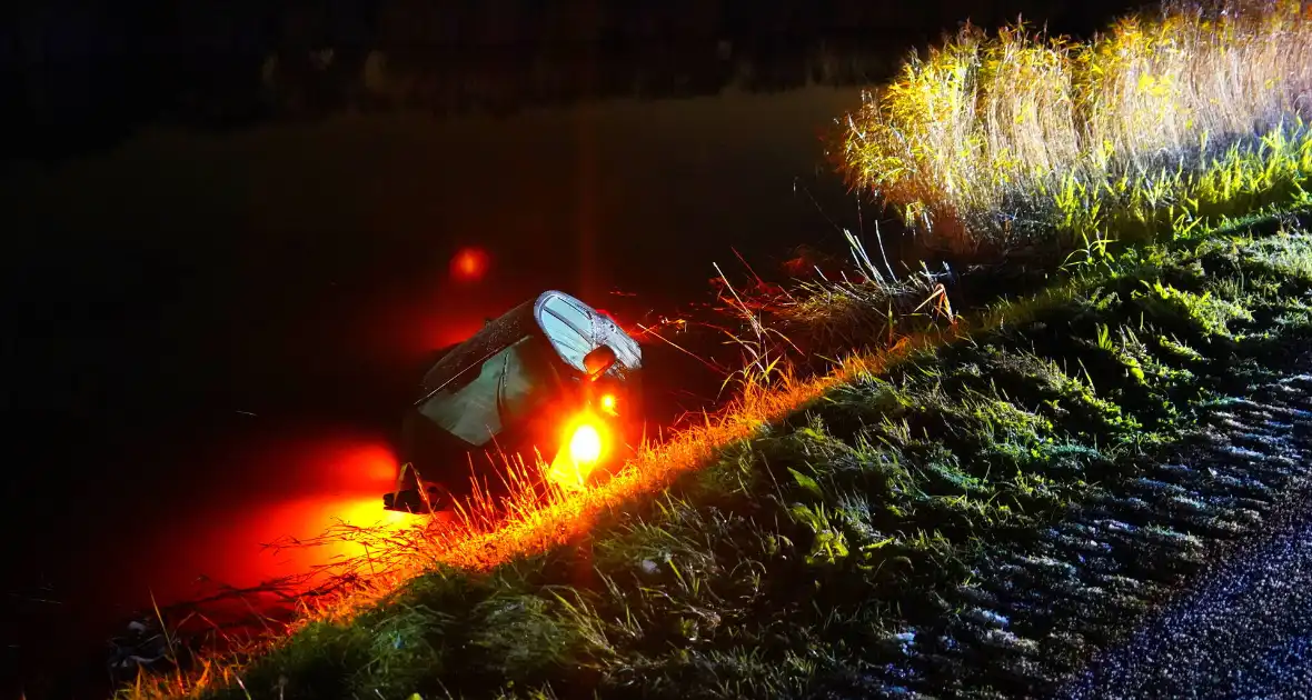 Twee auto's te water in bocht op gladde dijk